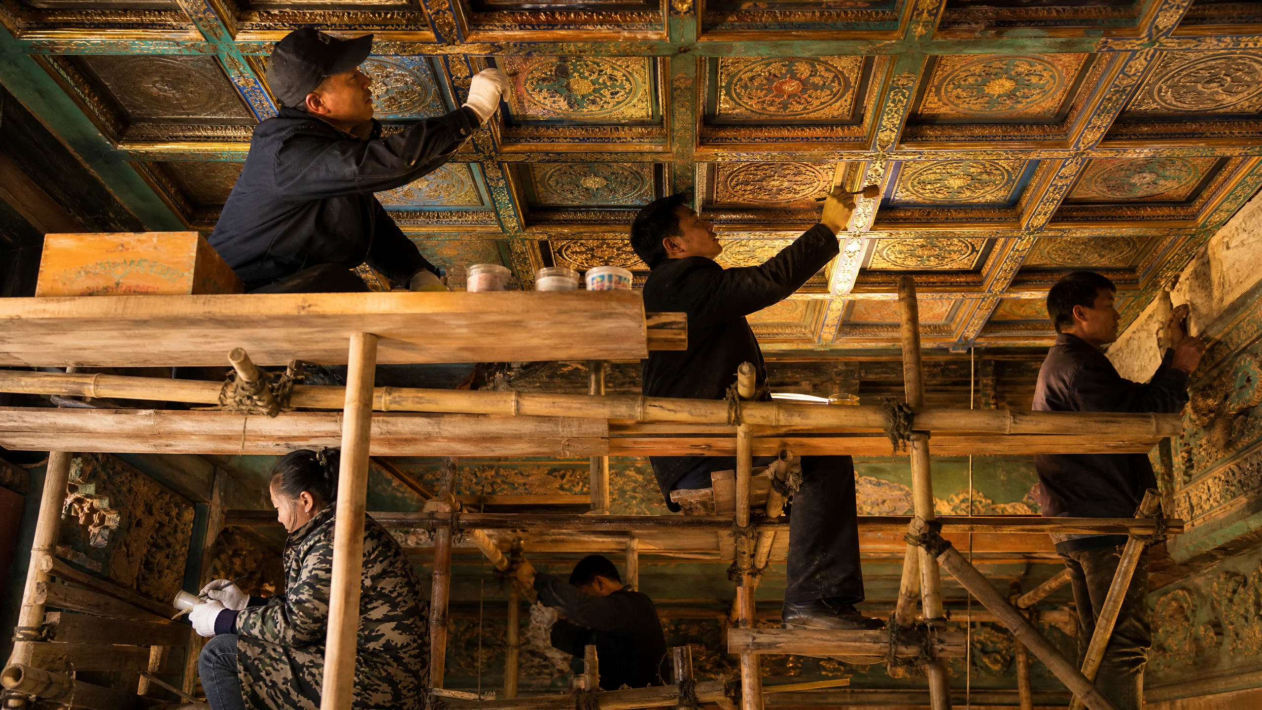 古建﻿筑​修复工程现场，工匠在脚手架﻿上修﻿复藻井彩画